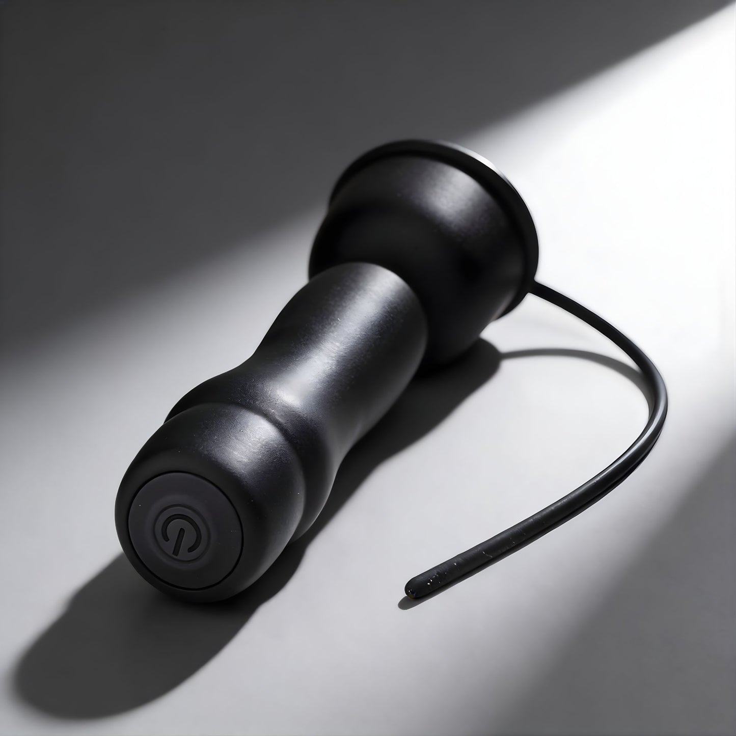 black vibrating penis head teaser with urethral sound attachment and suction cup base on neutral background