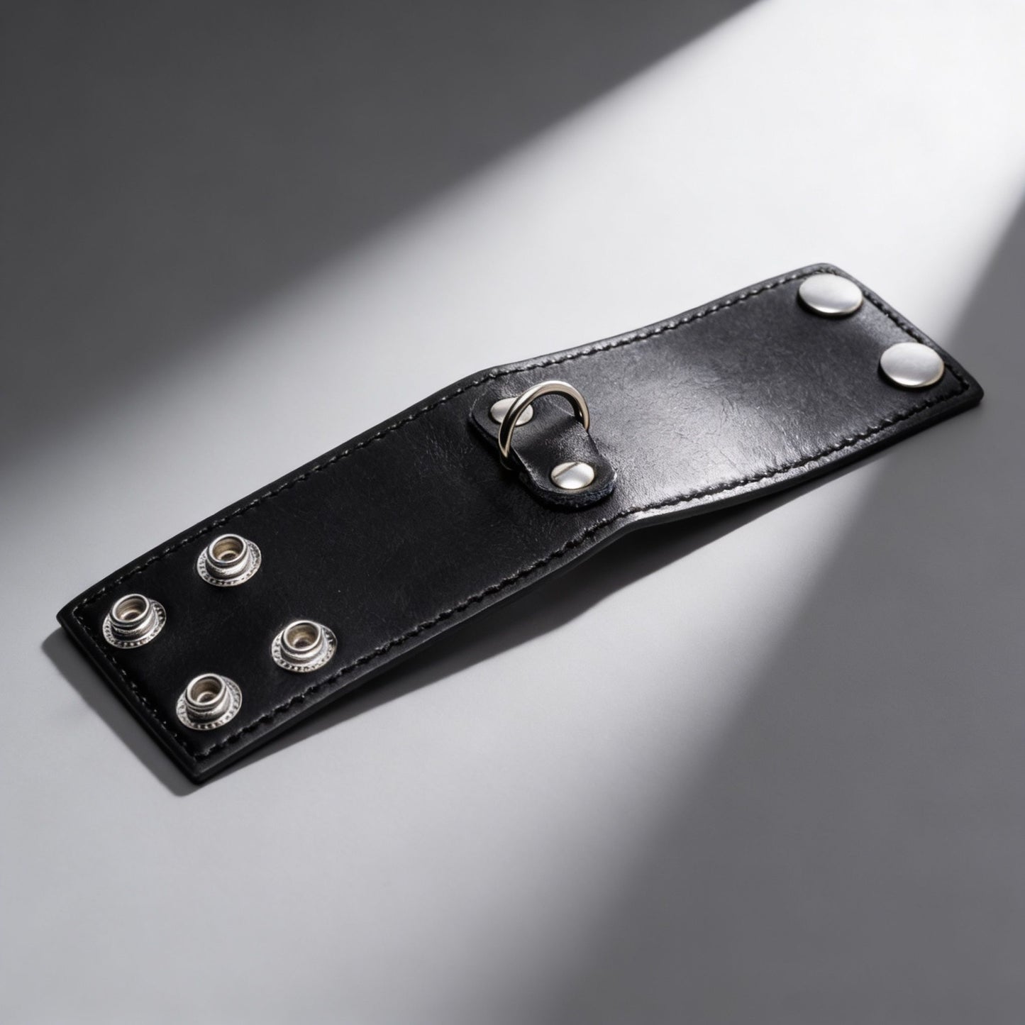 black leather 2 inch ball stretcher with snap closure and metal D-ring displayed on gray background
