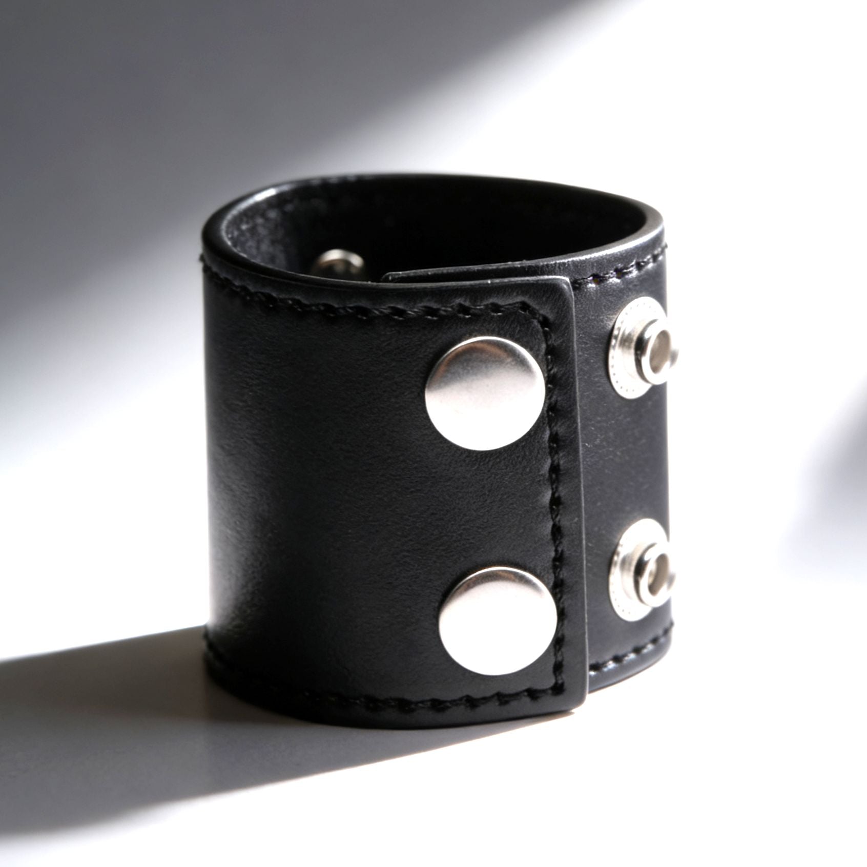 black leather 2 inch ball stretcher fastened into circular shape with silver snap closures on gray background