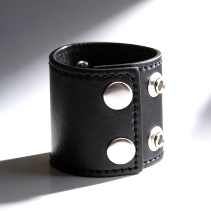 black leather 2 inch ball stretcher fastened into circular shape with silver snap closures on gray background