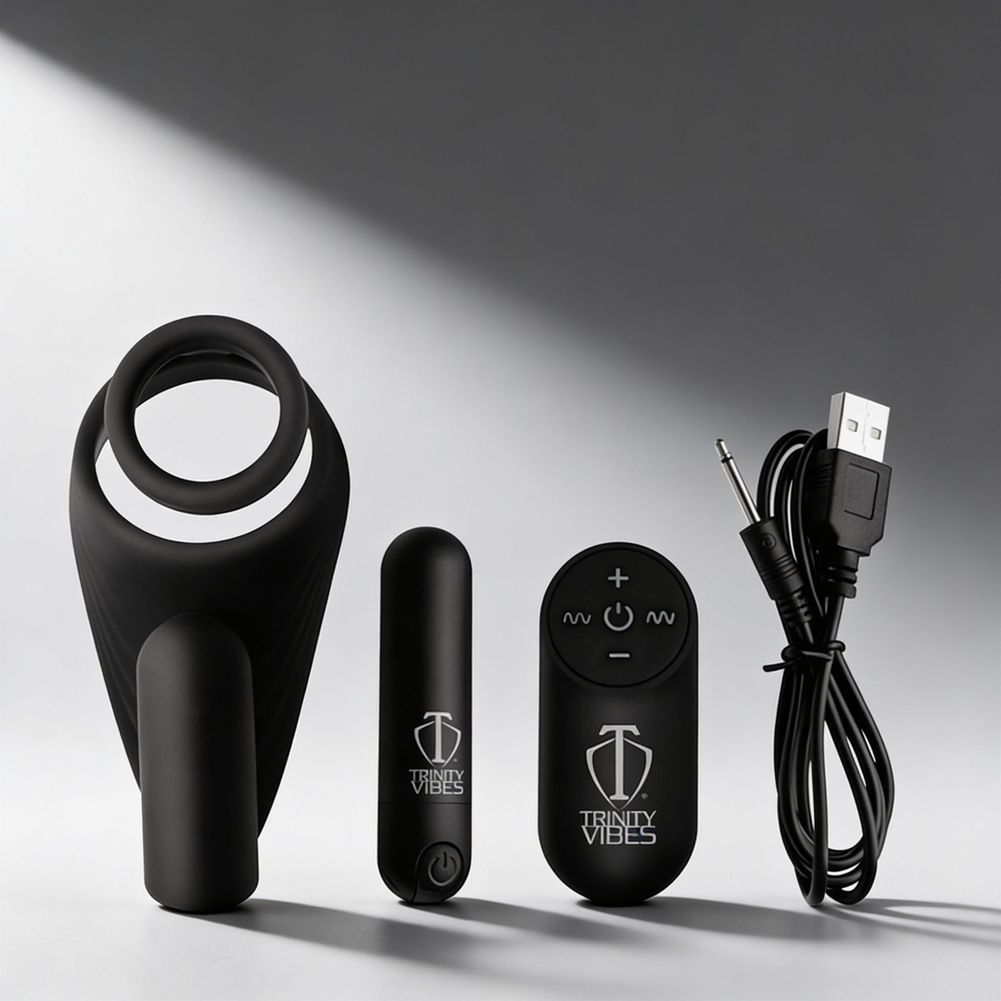 black silicone vibrating cock ring with curved taint stimulator shown with bullet vibrator remote control and USB charging cable on gray background