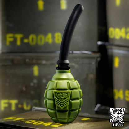 Green Grenade anal douche bulb with black nozzle standing on a stack of military ammo crates, Fort Troff gay gear at Boyzshop