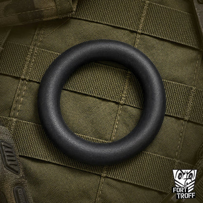 X-Wrap black silicone cock ring lying flat on olive tactical webbing, Fort Troff gay gear at Boyzshop
