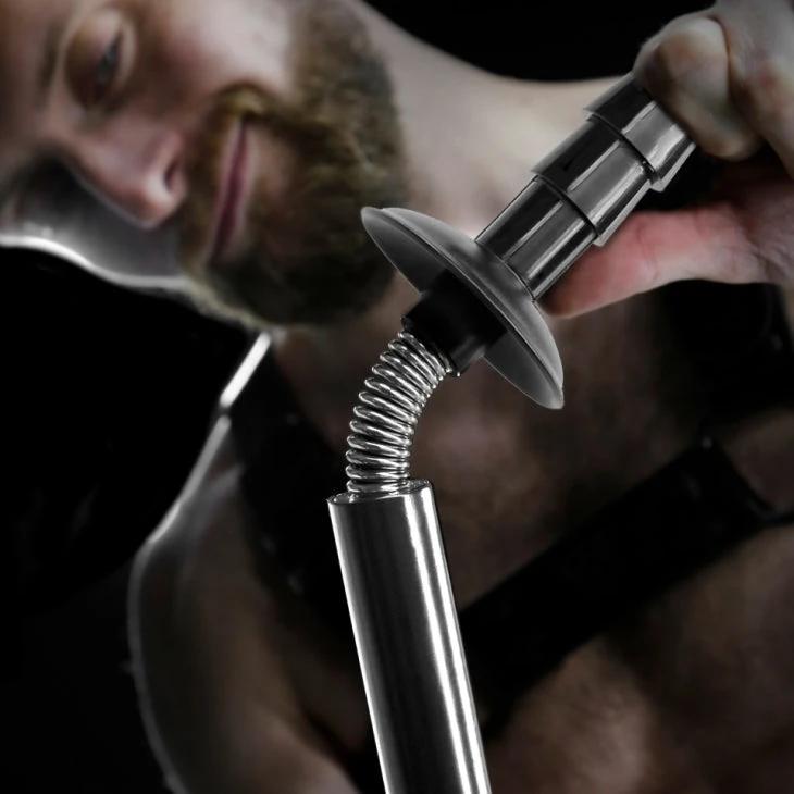 Bearded model holding the Spring Fuk Bar spring with its Vac-U-Lock tip up close, Fort Troff gay gear at Boyzshop