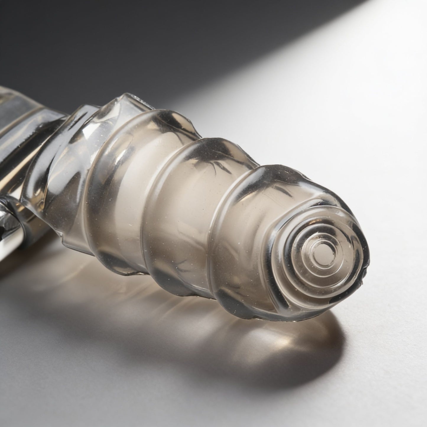 Detailed view of the textured insertable tip of a smoke-colored vibrating finger glove, featuring raised ridges and a rounded target-style end.