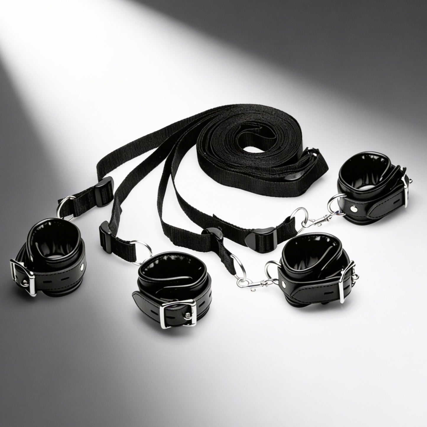 complete black faux leather bed restraint system with four padded cuffs and adjustable under-bed straps