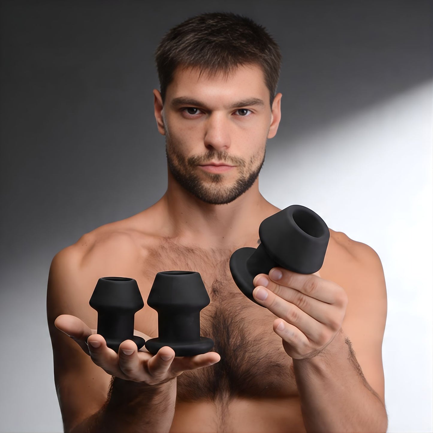 man holding three black silicone anal dilators in different sizes, showcasing graduated training set