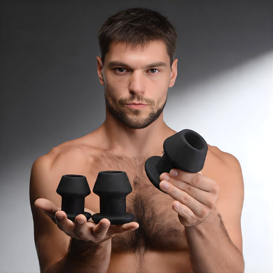 man holding three black silicone anal dilators in different sizes, showcasing graduated training set