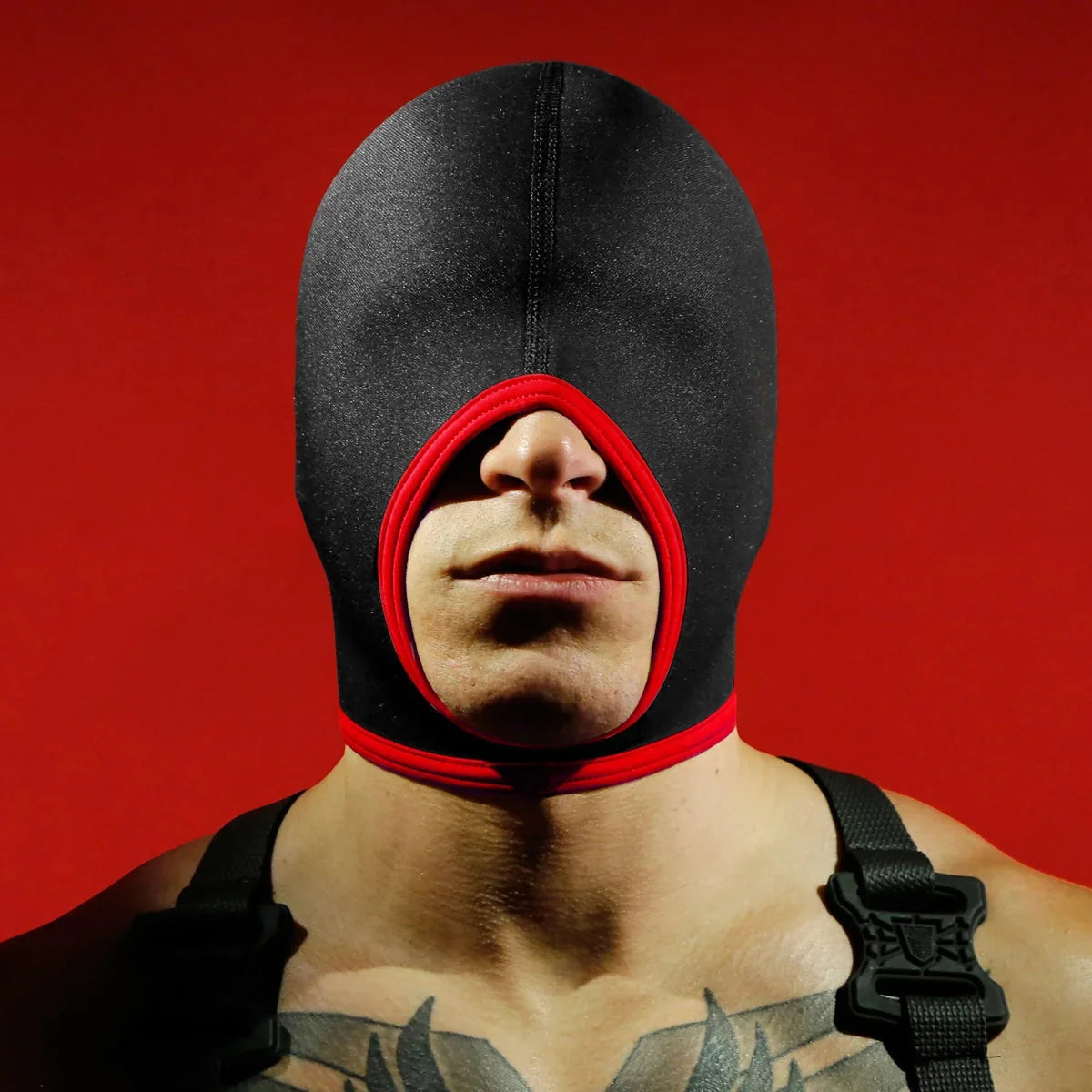 Blind Skullfuck bondage hood with red mouth trim worn over the eyes, open mouth, red backdrop, Fort Troff gay gear at Boyzshop