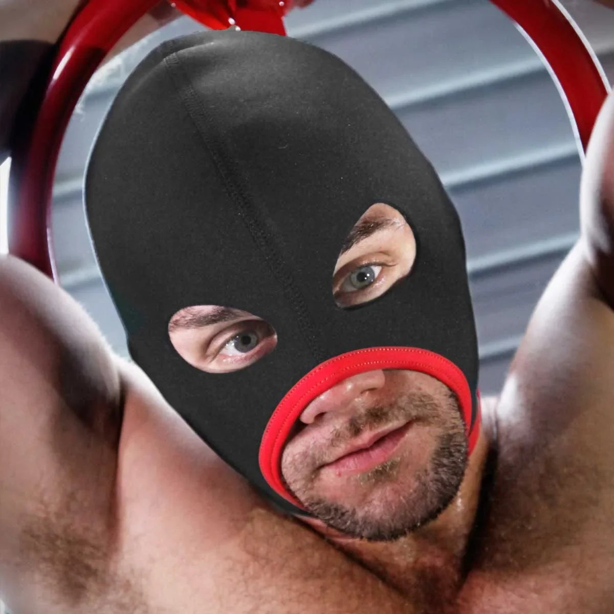 Bearded man in the red trim Skullfuck gimp mask, arms raised overhead, Fort Troff gay gear at Boyzshop