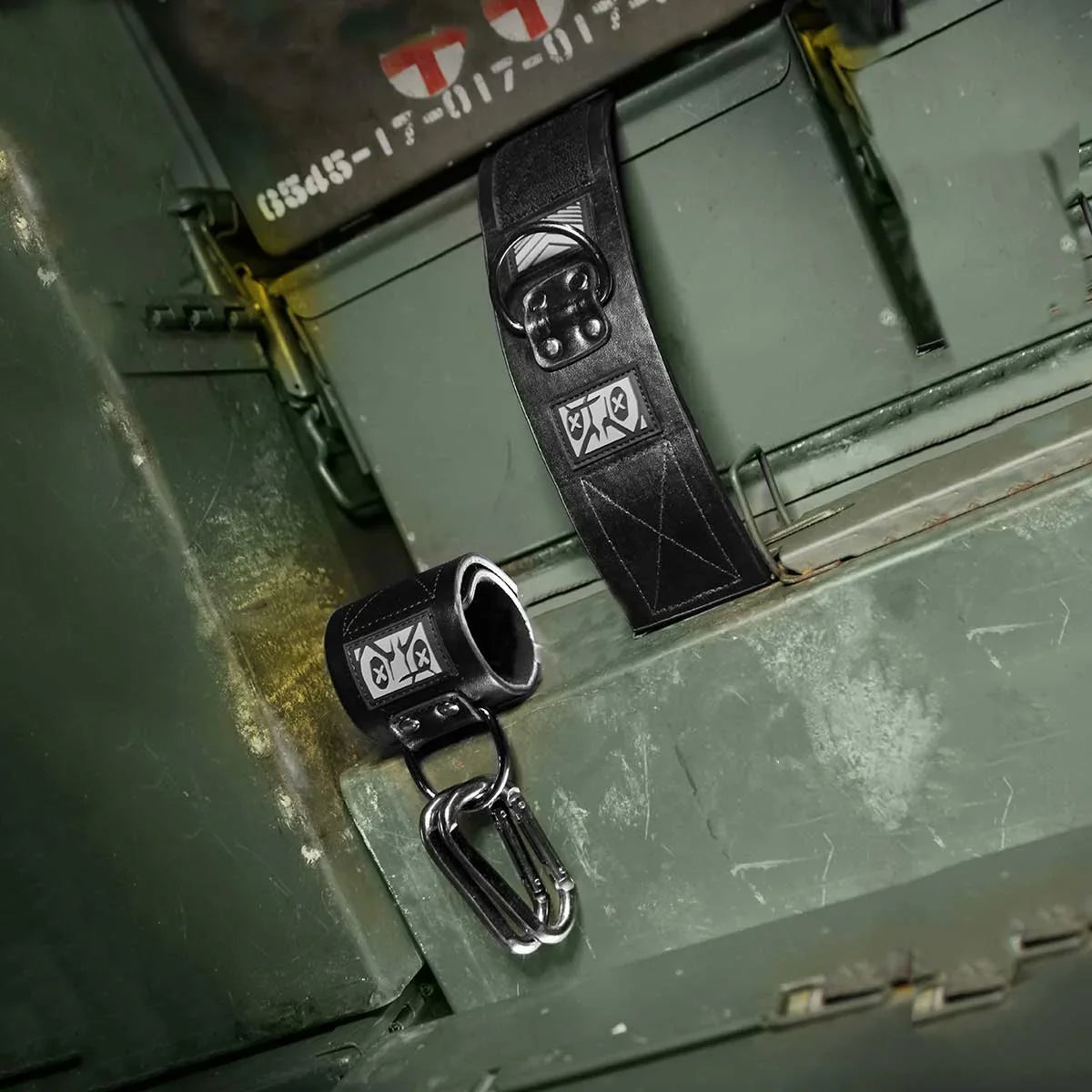 Pair of Neo neoprene wrist restraints with a carabiner resting on an olive ammo can, Fort Troff gay gear at Boyzshop