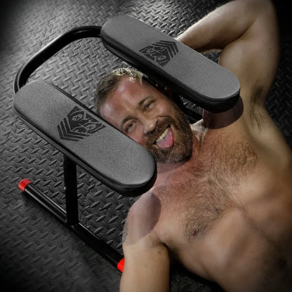 Grinning bearded man lying under the Ready Rimmer rimming chair, Fort Troff gay gear at Boyzshop