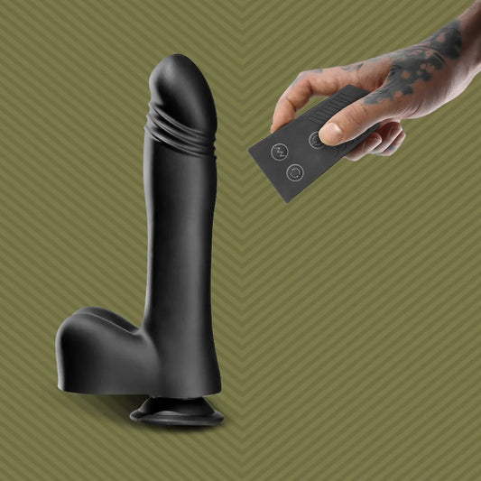 Black Piston Thruster thrusting dildo on a suction base, tattooed hand holding the remote, Fort Troff gay gear at Boyzshop