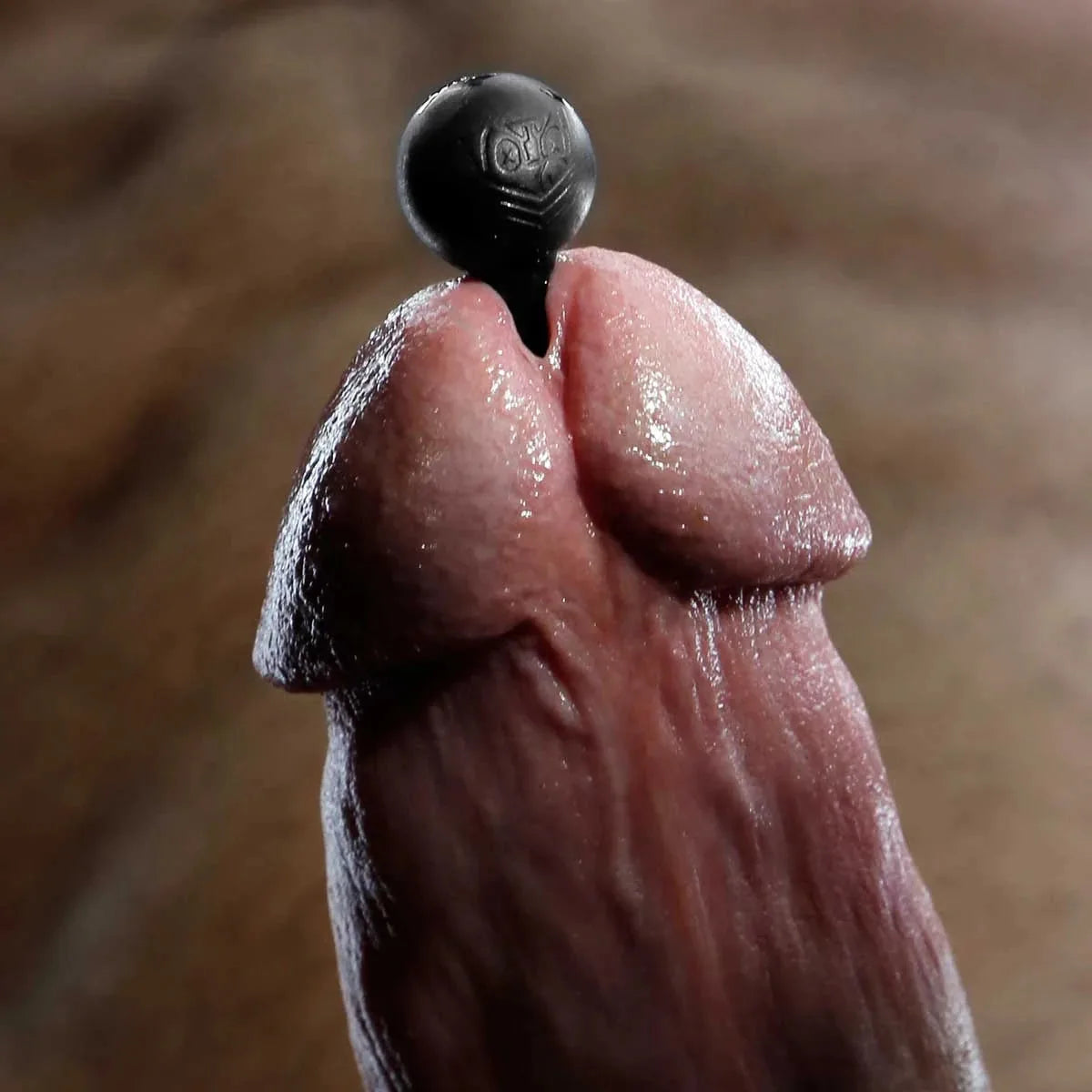 Close-up of a hollow penis plug seated in the slit of a wet cock head, Fort Troff gay gear at Boyzshop