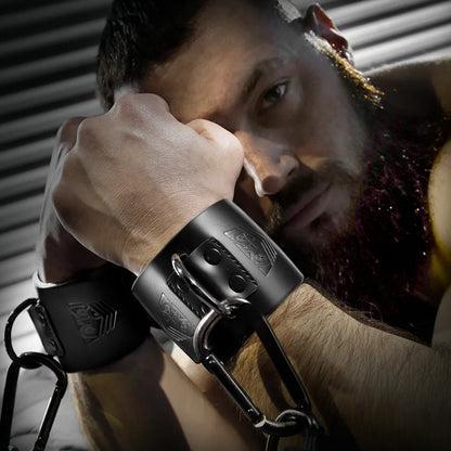 Bearded model resting his head on a leather wrist cuff clipped to a carabiner chain, Fort Troff gay gear at Boyzshop