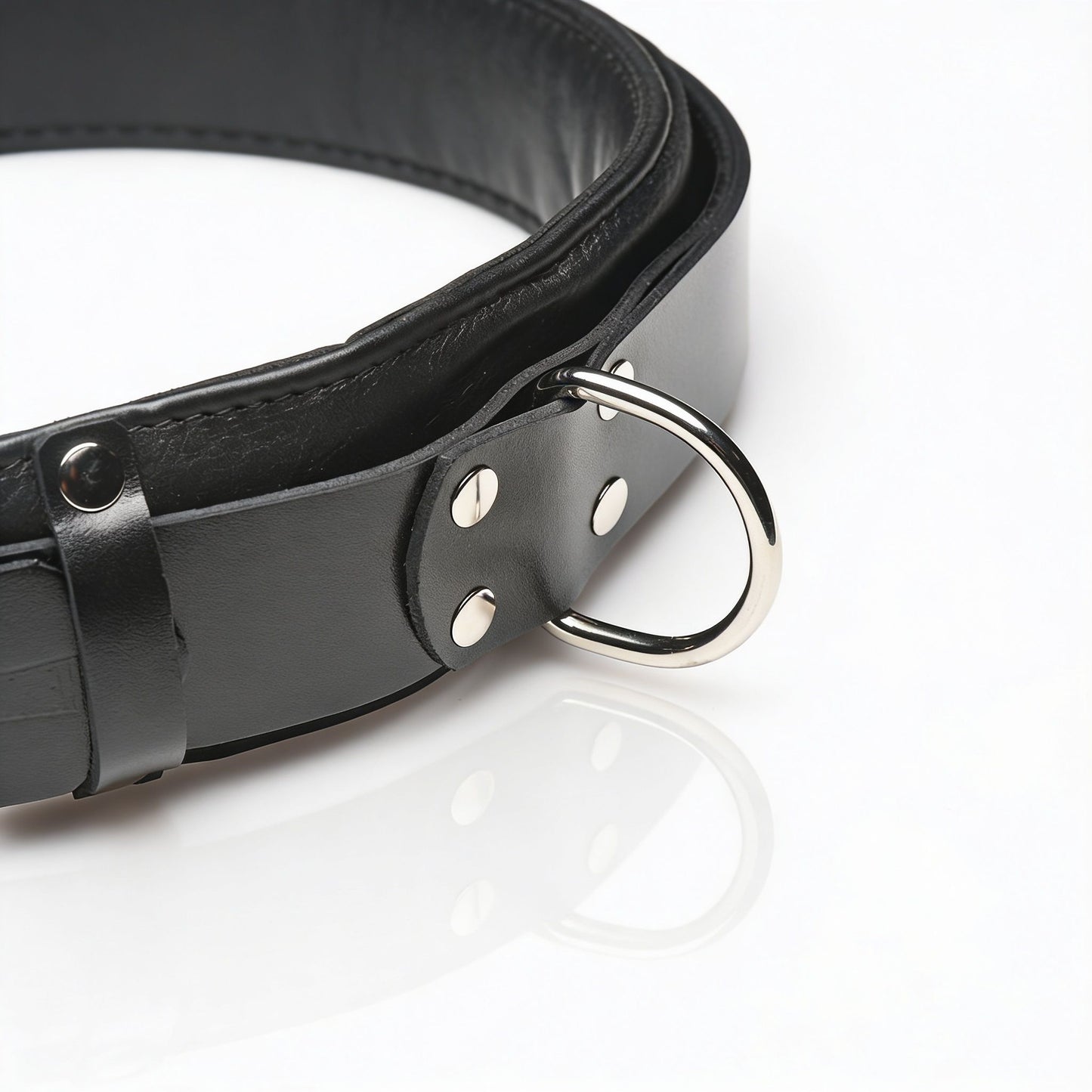 close-up detail of black leather thigh sling restraint featuring silver D-ring attachment and padded leather cuff