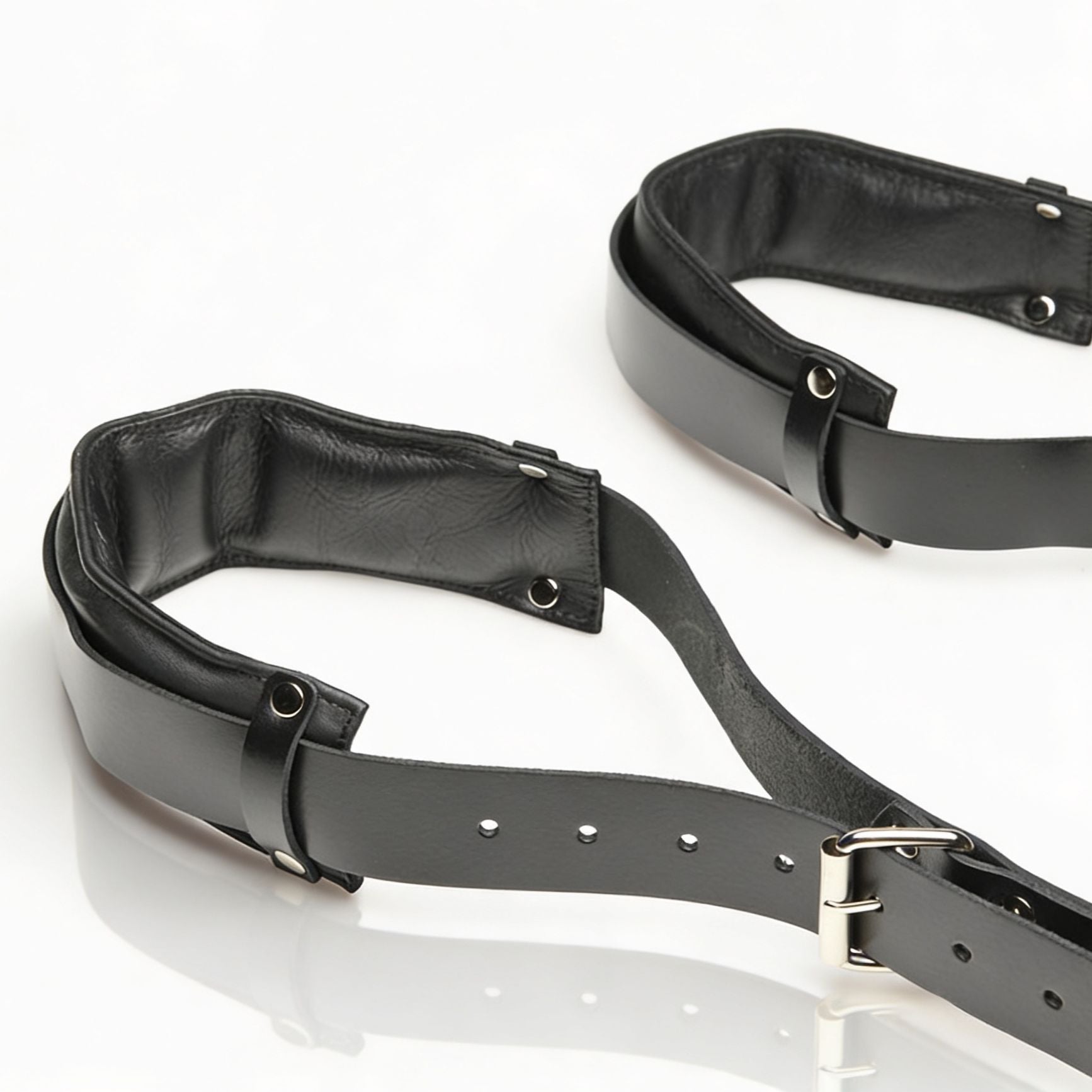 black leather thigh sling restraint with padded cuffs, adjustable straps, and silver hardware displayed on white background