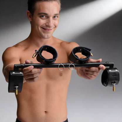 locking wrist and ankle spreader bar with adjustable metal bar black padded cuffs and padlocks displayed in hands