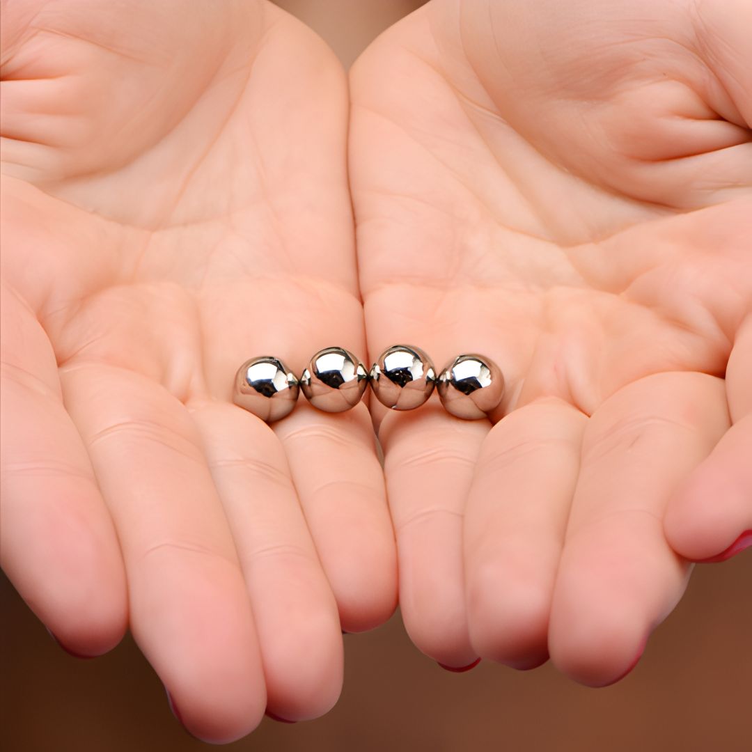 set of small chrome magnetic orbs displayed in open hands for scale and size reference