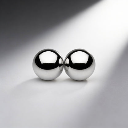 two polished silver magnetic metal orbs touching together on gray background with dramatic lighting