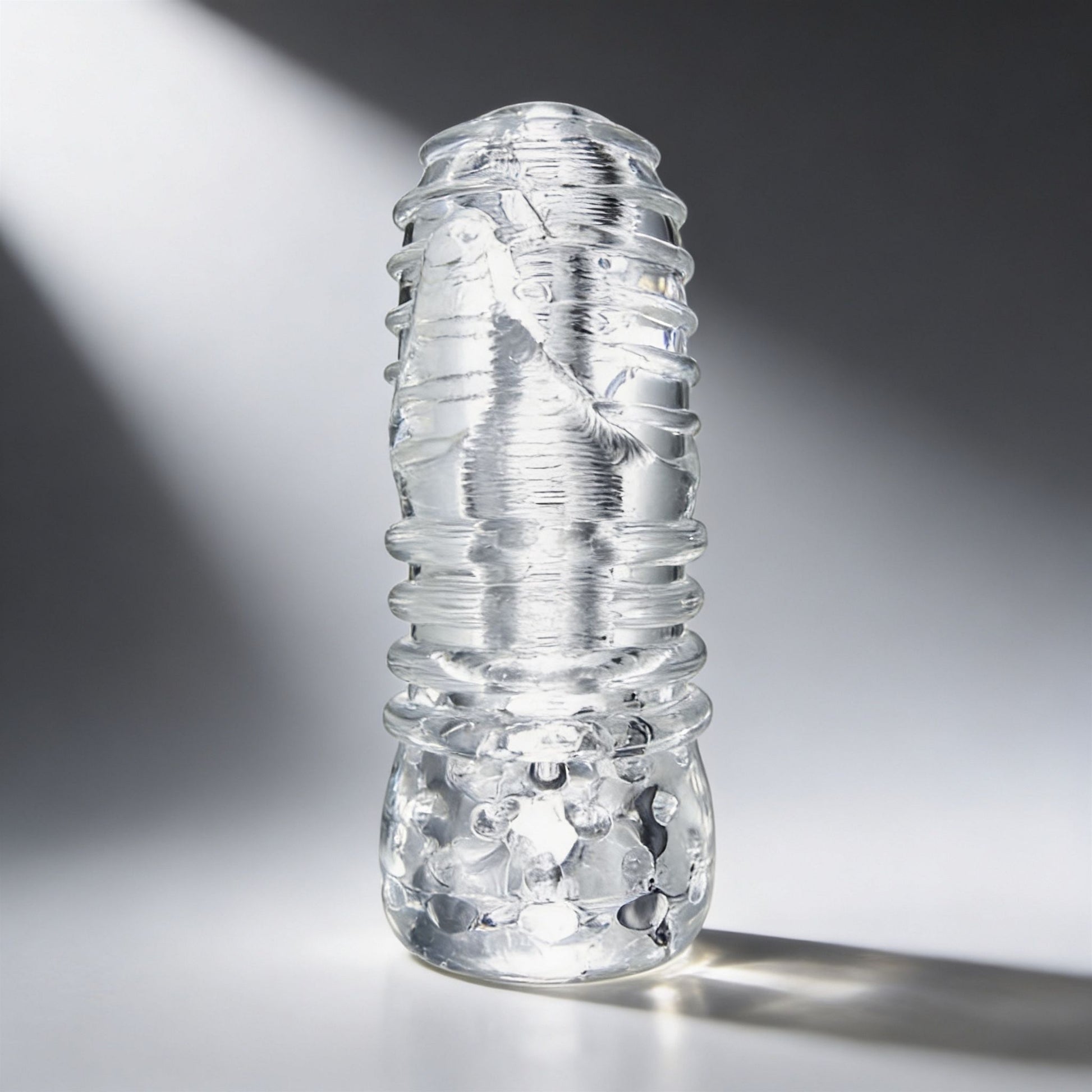 Palm-Tec LX20 Intense Stroker standing upright with a clear flexible sleeve featuring external ribs and a compact handheld design