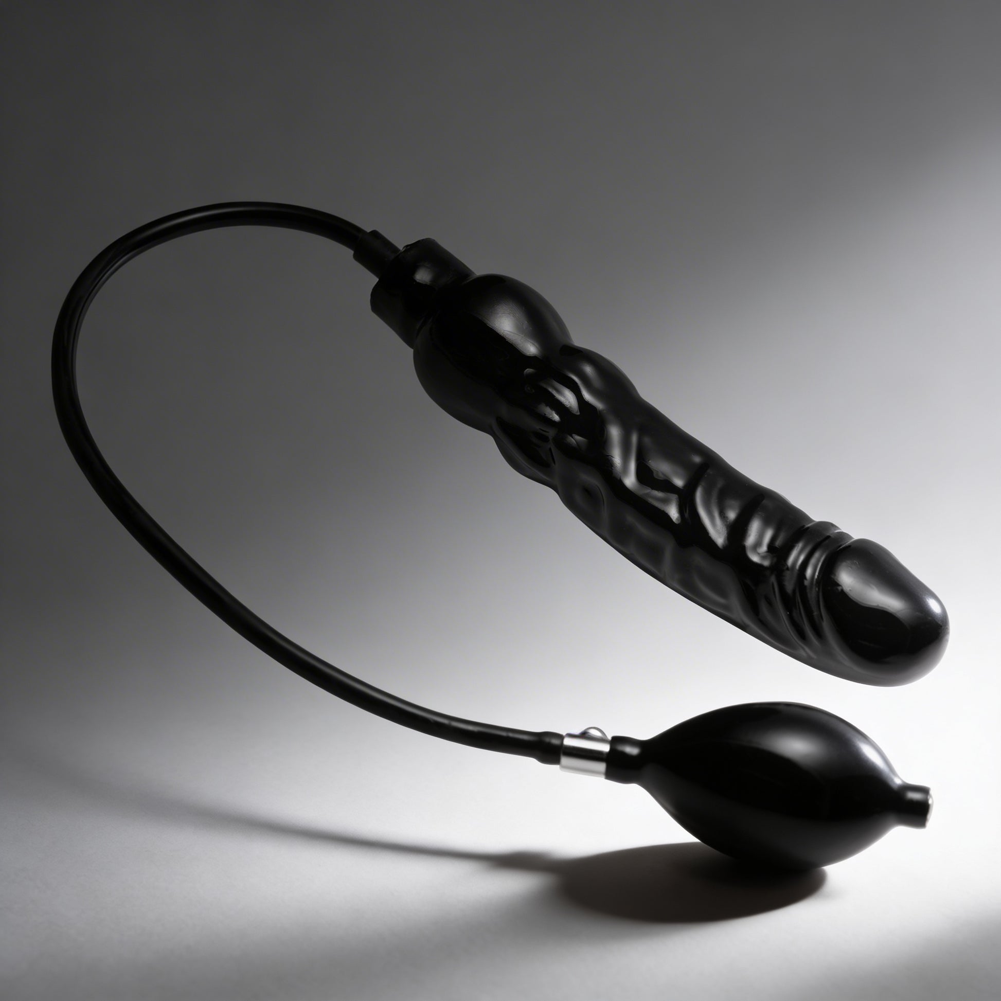 black Primal inflatable dildo with attached inflation pump and textured curved shaft on dark gray background
