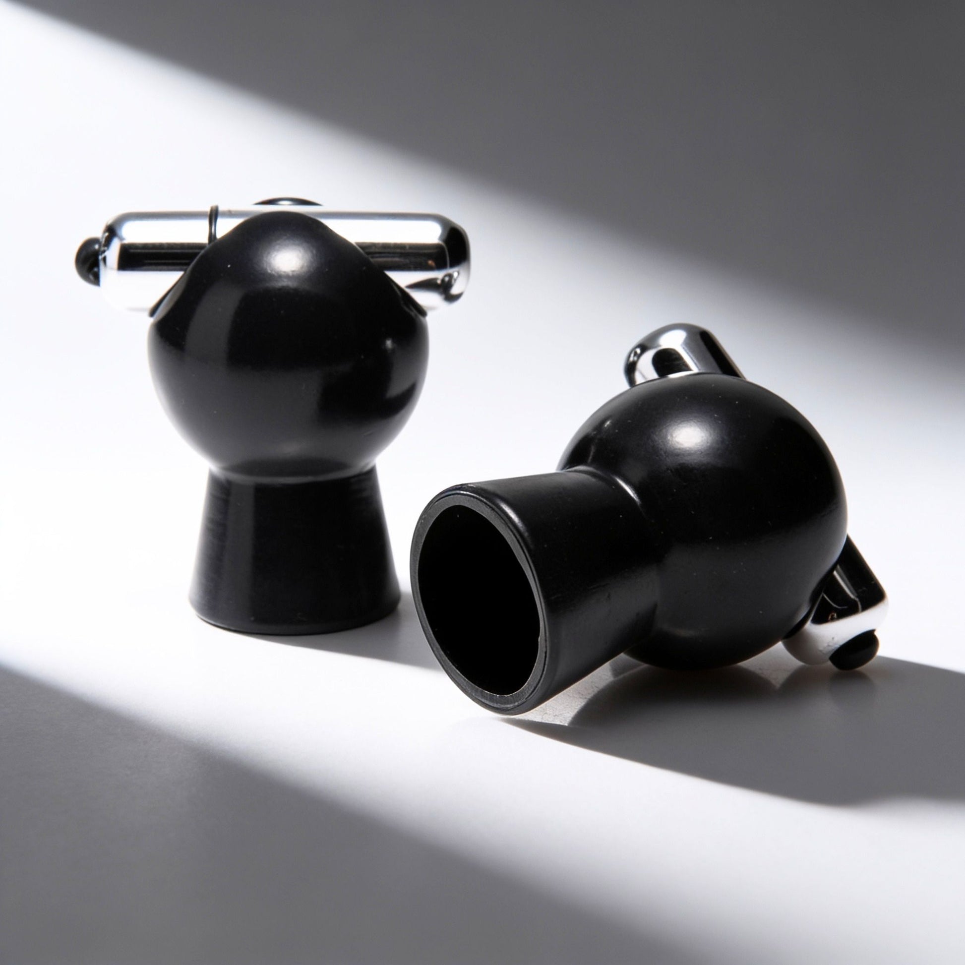 Pair of black vibrating nipple suckers displayed on a white surface, showcasing the vacuum suction cups, removable bullet vibrators, and sleek glossy finish.