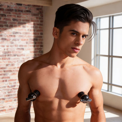 Male model wearing black vibrating nipple suckers, demonstrating the compact suction cup design and hands-free fit on the chest in a bright studio setting.