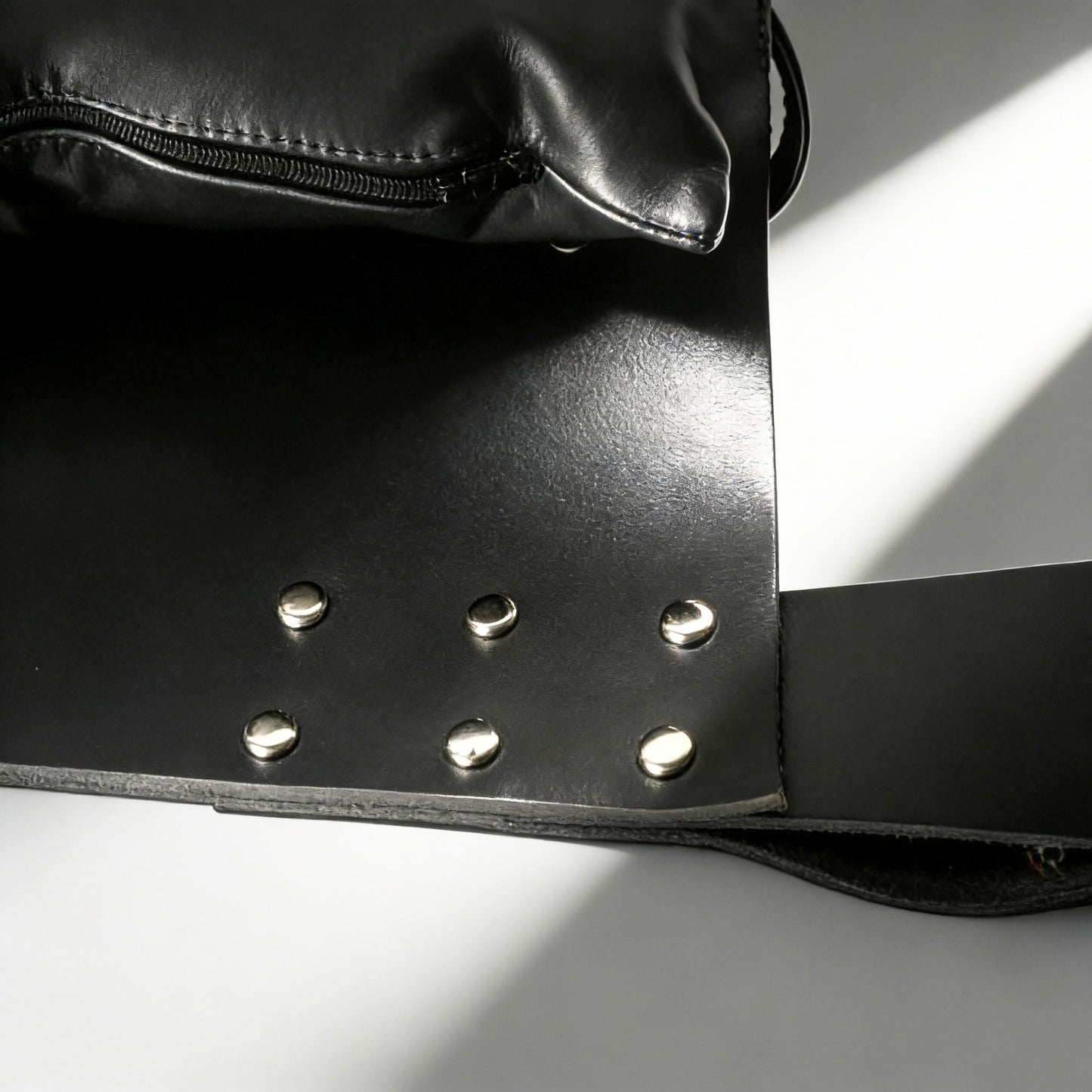 close-up of black leather sling construction with silver rivets and padded support pillow detail